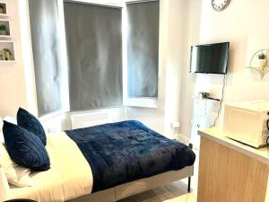 a bedroom with a bed and a tv and a window at Southall Stays near Heathrow UB2 in Southall
