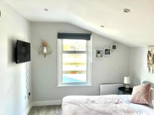 a white bedroom with a bed and a window at Southall Stays near Heathrow UB2 in Southall