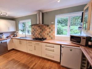 シドマスにあるMeadow Viewの白いキャビネットとシンクと電子レンジを備えたキッチン +8枚の写真