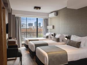 布宜诺斯艾利斯Casa Joseph的酒店客房设有三张床和大窗户