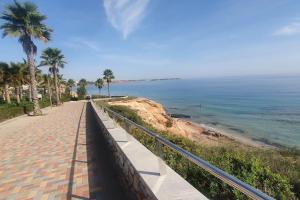 un marciapiede accanto a una spiaggia con palme e l'oceano di Superbe appartement calme vue mer a Orihuela Costa