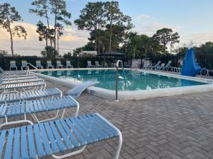 uma piscina com cadeiras azuis e um monte de água em Cottage in Arbor Terrace Resort em Bradenton