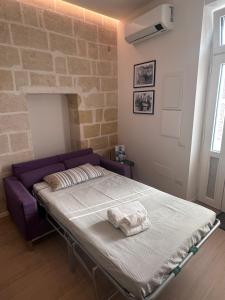 um quarto com uma cama e um sofá roxo em Il Tufo In Festa em Matera