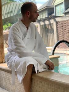 a man sitting on a ledge next to a swimming pool at Montigo Resorts, Somerset in Shepton Mallet