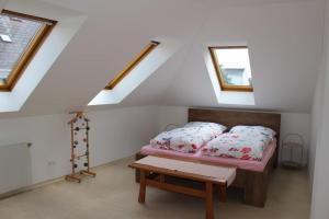 ein Schlafzimmer mit einem Bett, einem Tisch und zwei Fenstern in der Unterkunft Ferienwohnung zur goldenen Breze in Pinkafeld