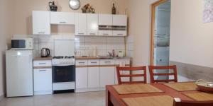 a kitchen with white appliances and a table with chairs at Móricz Vendégház in Sárospatak