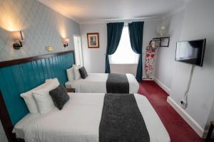 Habitación de hotel con 2 camas y TV en Rising Sun Hotel by Greene King Inns, en Cheltenham