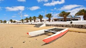 a red and white boat sitting on the beach at Apartamento Tierra, Primera línea Mar in Playa Honda