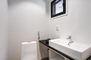 a white bathroom with a sink and a toilet at Villa Syreeni - Seafront/Jacuzzi 