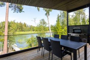 a table and chairs on a deck with a view of a river at Villa Syreeni - Seafront/Jacuzzi 