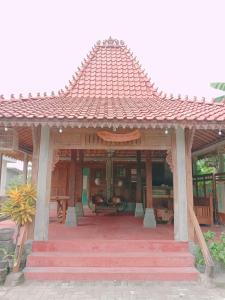 a wooden pavilion with a red roof on a patio at Rumah Ukhi in Yogyakarta
