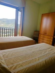 a bedroom with two beds and a large window at Albergo Grumentum in Grumento Nova