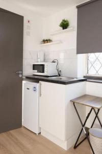 a white kitchen with a microwave and a refrigerator at UB2 Suites - Heathrow London in Southall