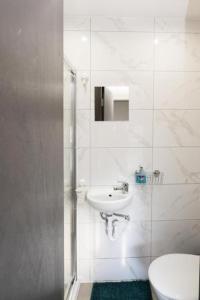 a white bathroom with a sink and a toilet at UB2 Suites - Heathrow London in Southall