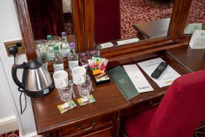 een houten tafel met glazen en flessen erop bij Rising Sun Hotel by Greene King Inns in Cheltenham