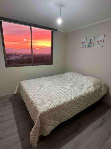a bedroom with a bed and a large window at Departamento centro Quillota con estacionamiento in Quillota
