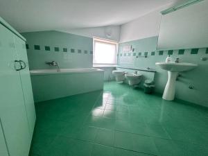 een groene badkamer met 2 toiletten en een wastafel bij Casa Olivastri in Treglio