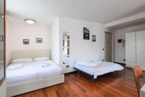 two beds in a room with white walls and wooden floors at PrimoPiano - Euclide in Milan