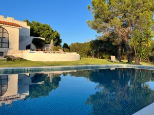 a swimming pool in front of a house at Cabanas Jardim & Ria in Cabanas de Tavira