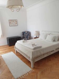 a white bedroom with a large bed and a wooden floor at Апартамент BOHO CHIC 2 Free parking in Varna City