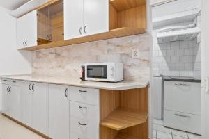 eine Küche mit weißen Schränken und einer Mikrowelle auf der Theke in der Unterkunft Apartament Helena in Oradea