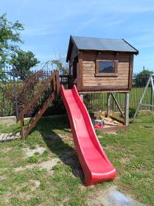 a red slide in front of a play house at Pokoj agroturystyczny in Mieroszyno