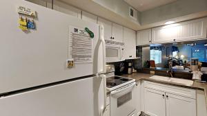 uma cozinha com armários brancos e um frigorífico branco em Experience Tranquility at Summertree Village Condo em Myrtle Beach