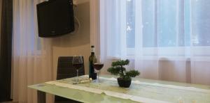 Una mesa con una copa de vino y una botella y una planta. en Napolá apartman, en Balatonalmádi