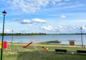 a park with playground equipment and a dock on the water at Lakeview Retreat in Vievis in Vievis