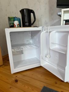 a white refrigerator with its door open on a wooden floor at Posti 8 aiamaja in Haapsalu