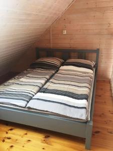 een bed in een kamer met een houten plafond bij Apartamenty Cztery Siostry in Zastań