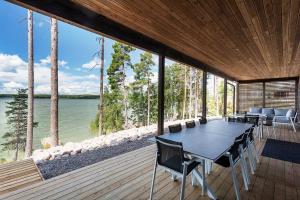 una mesa y sillas en una terraza con vistas al agua en Saunamäki Resort - Seafront Luxury, en Salo