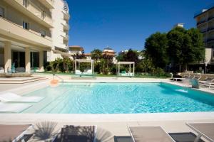 a large swimming pool with chairs and a building at Hotel Beaurivage in Cattolica