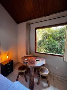 a room with a table and two stools and a window at Cantinhos do Cipó - Chales privativos com hidro in Serra do Cipo