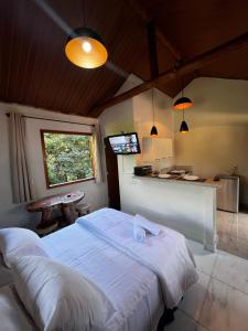 a bedroom with a large white bed and a kitchen at Cantinhos do Cipó - Chales privativos com hidro in Serra do Cipo