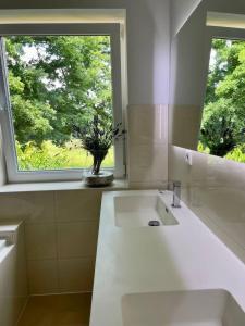La salle de bains blanche est pourvue d'un lavabo et d'une fenêtre. dans l'établissement Familienfreundlichen Apartment mit traumhaft grüner Aussicht, à Hambourg