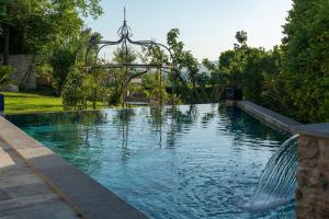 een zwembad met een fontein in een tuin bij MAISON D'HOTES LA GOURGUILLE in Barjac