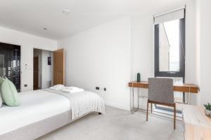 a white bedroom with a bed and a desk at The Camden Apartment in London