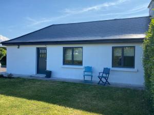 a white house with two chairs in the yard at mary-tim's Cromane Cross near Killorglin in Killorglin