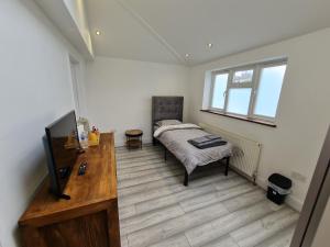 Dormitorio con cama, escritorio y TV en Stylish Suites with kitchenette, en London Colney