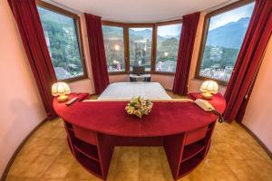 een grote rode badkuip in een kamer met ramen bij Hotel Mirage in Chiesa in Valmalenco