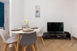 a dining room with a table and chairs and a tv at Młyny Gdańskie Apartment with Terrace, Gym & Playground by Renters in Gdańsk