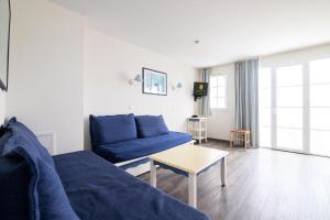 a living room with a blue couch and a table at Residence Port du Crouesty Cap Ocean - maeva Home in Arzon