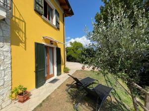 ein gelbes Haus mit zwei Stühlen im Hof in der Unterkunft Villa dei Roveri in Tignale