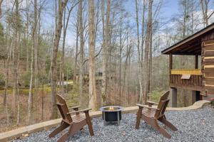 two chairs and a fire pit on the patio of a cabin at Boozy Bear Bungalow romantic cabin 5 mins 2 downtown with hot tub and fire pit in Gatlinburg