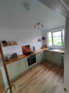 a kitchen with white cabinets and a sink and a window at A view to Caol, Fort William in Fort William