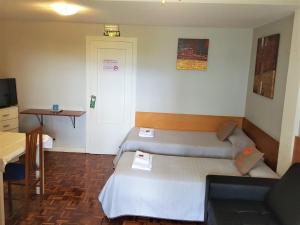 パンプローナにあるPensión Pamplonabedsのベッド2台、デスクが備わる小さな客室です。