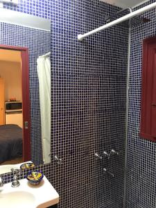 a blue tiled bathroom with a sink and a shower at Monoambiente con baño privado y cocineta dentro de casa in Buenos Aires
