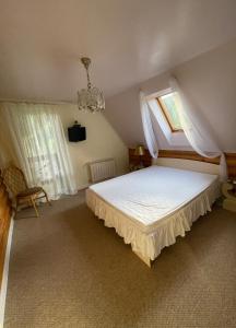 a bedroom with a bed with a window and a chandelier at Bukovynskiy Zatyshok Chalet in Bukovel