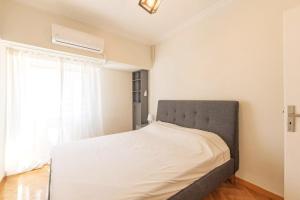 a bed in a bedroom with a large window at Spacious 3 bedroom apt in Eksarchia in Athens